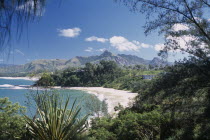 Libanona Beach with view across plants and vegetation towards sandy stretch of beach and sea with mountains in the distance