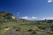 Road to Ambalavao. View across green flood plain  towards clay brick kilns and tree covered hills