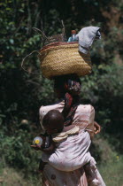 Near Ambositra. Portrait of a woman carrying a baby in a sling on her back and wicker baskets on her head