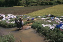 Near Ambositra. Women doing laundry in a river with the clothes left to dry in the sun along the river banks