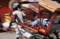 Rickshaw driver traveling along road in motion blur