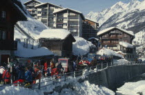 Crowded ski resort in snow with mountain backdrop.Swiss Alps