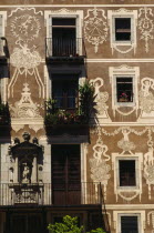 Decorated exterior of flats on the Plaza Delfi with potted plants and flowers on the balconies and window sills.  Catalunya