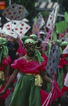 Carnival precession with girls dressed in pink and green costumes holding large plain card props