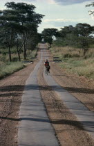 Cyclist carrying passenger on the crossbar on strip tar road bike   bicycle