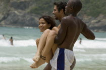 Two young men  carrying a young woman down to the sea  Choroni beach