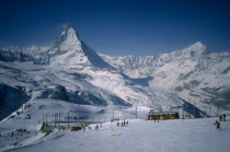 Skiers on slopes in foreground with Matterhorn behind.