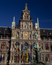 Grote Markt or Main Square.  The Brabo Fountain with the Town Hall facade hung with flags behind . Flanders Flemish Region