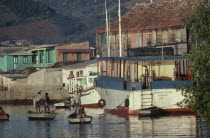 Harbour with moored boats and men in shallow wooden rowing boats.