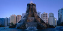 The Volcano Fountain. Large tiered fountain with water cascading from circular top and high rise modern buildings behind. United Arab Emirates