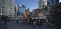 The Old Souk. Exterior of jewellery and clothes shops with people walking through paved area in front and high rise modern buildings behind.Market United Arab Emirates