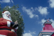 Christmas at Shell factory. Santa statue in the foreground and chimney behind with model legs coming out of the top