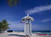 Lifeguard hut on occupied sandy beach with American flag flying