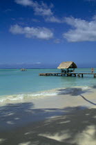 View across shoreline toward wooden boat jetty with hut