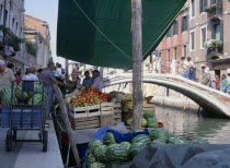 Fruit and vegetable stall on a boat on the riverbank near a small bridge