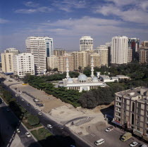 Elevated view over mosque surrounded by trees and  high rise buildings near a road with trafficMoslem United Arab Emirates