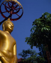 Charoen Krung.  Golden Buddha statue in temple grounds.New Road