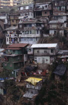 Poor quality housing on steep hillside strewn with litter. rubbish   pollution