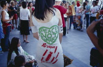 Anti-war rally outside MBK shopping mall protesting against Bush and Blair.  Woman wearing dress with Peace Not War slogan printed on back.