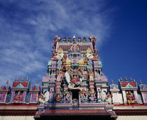 Sri Mariamman Temple.  Part view of exterior roof and gopuram painted tower decorated with brightly painted figures of Hindu gods and characters.