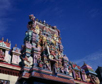 Sri Mariamman Temple.  Angled part view of exterior and gopuram painted tower decorated with brightly painted figures of Hindu gods and characters.