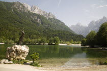 The famous Ibex statue at Lake Jasna just a ten minute walk form the centre of the town at the entrance to Velika Pisnica near the road to Vrsic Mountain Pass with Mounts Razor and Prisank in th backg...