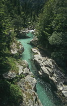 The clear green water of the Soca River flowing through a narrow gorge below Felika Korita Soce a narrow wooden suspension bridge the rocks have been shaped by the power of the water  Clear blue wat...