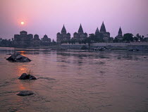 The domes and spires of the chhatris memorials to Bundelkhands former rulers from across the Betwa River at sunset  Heritagehistoricalsilhouettestourist attractionquietsilenteeriemonumentsin...