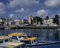 The Carenage seen from across the sea  with buildings church tower cars  boats on water in foreground