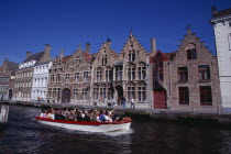 Tourist boat on canal with guide pointing out traditional waterside architecture.