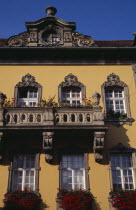 Detail of yellow painted facade of town building with stone balconies and window boxes filled with red geraniums and other flowers.Eastern Europe  Eastern Europe