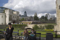 Tourists using their mobile phone outside the Tower of London with the Gherkin Building behind.United Kingdom  30 St Mary Axe Great Britain UK