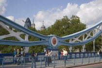 The Tower of London and the Gherkin seen through a detail of  Tower bridge with pedestrians crossing.United Kingdom  30 St Mary Axe Great Britain UK