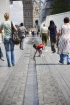 People walking passed man made stream toward GLA town hall and Tower Bridge.United Kingdom  Greater London Authourity Southbank Great Britain UK