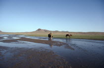 Horse back rider wading through shallow river.