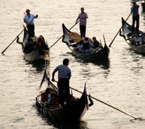 Gondoliers carrying sightseeing tourists on their gondolas at sunset on the Grand Canal