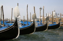 Ferros or bows of Gondolas moored in the Molo San Marco basin with the Baroque church of Santa Maria della Salute on the Grand Canal in the distance