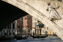 A gondola carrying tourists passes beneath the Rialto Bridge over the Grand Canal