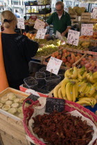 Fruit and vegetable stall in the Rialto market with shopper and vendor