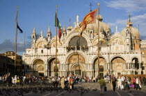 Tourists feeding pigeons in Piazza San Marco in front of St Marks Basilica