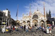 Tourists feeding pigeons in Piazza San Marco in front of St Marks Basilica