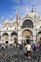 Tourists feeding pigeons in Piazza San Marco in front of St Marks Basilica