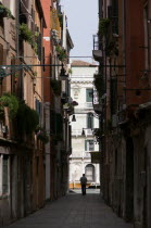 View down a narrow street to the Grand Canal in the San Polo and Santa Croce district with a man in silhouette by the canal