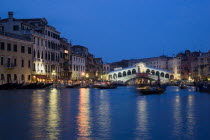 The Rialto Bridge spanning the Grand Canal illuminated at night with the canal busy with various water transport