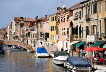 Fondamenta Degli Ormesini in Cannaregio district with boats moored along the canal and people walking along the pavement