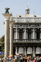 Tourists walk in the Piazetta below the winged Lion of Saint Mark on the Column San Marco and the Column of San Teodoro