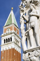 Stone carving of Eve and The Serpent on the corner of the Doges Palace in the Piazzetta with the Campanile tower in Saint Marks Square beyond