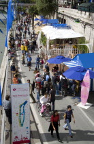 The Paris Plage urban beach. People strolling beside the River Seine along the Voie Georges Pompidou usually a busy road now closed to traffic opposite the Ile de la Cite with a map showing the attrac...