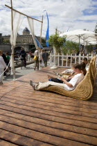 The Paris Plage urban beach. People strolling between the River Seine and other people lying on whicker chairs along the Voie Georges Pompidou usually a busy road  now closed to traffic opposite the I...