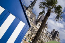 The Paris Plage urban beach. Young people playing beach volleyball behind beach huts in front of the Hotel de Ville Town Hall